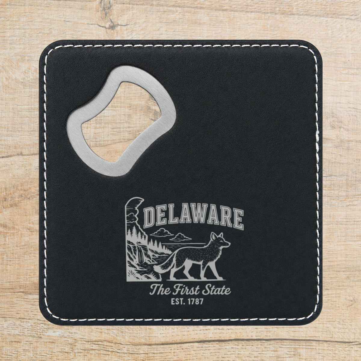 Black leatherette bottle opener coaster laser engraved with a Delaware design of a gray fox, a waterfall and pine forest