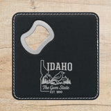 Black leatherette bottle opener coaster laser engraved with an Idaho design of a mountain bluebird, mountains and pines