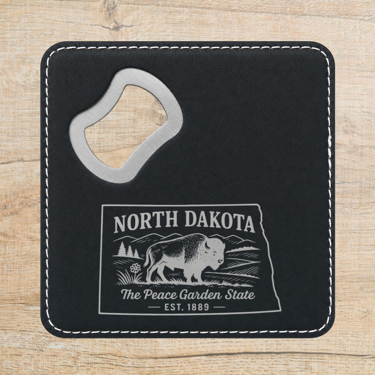 Black leatherette bottle opener coaster laser engraved with a North Dakota design of a bison on the plains