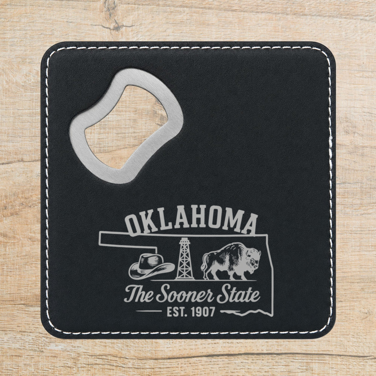 Black leatherette bottle opener coaster laser engraved with an Oklahoma design of a cowboy hat, an oil derrick and a bison