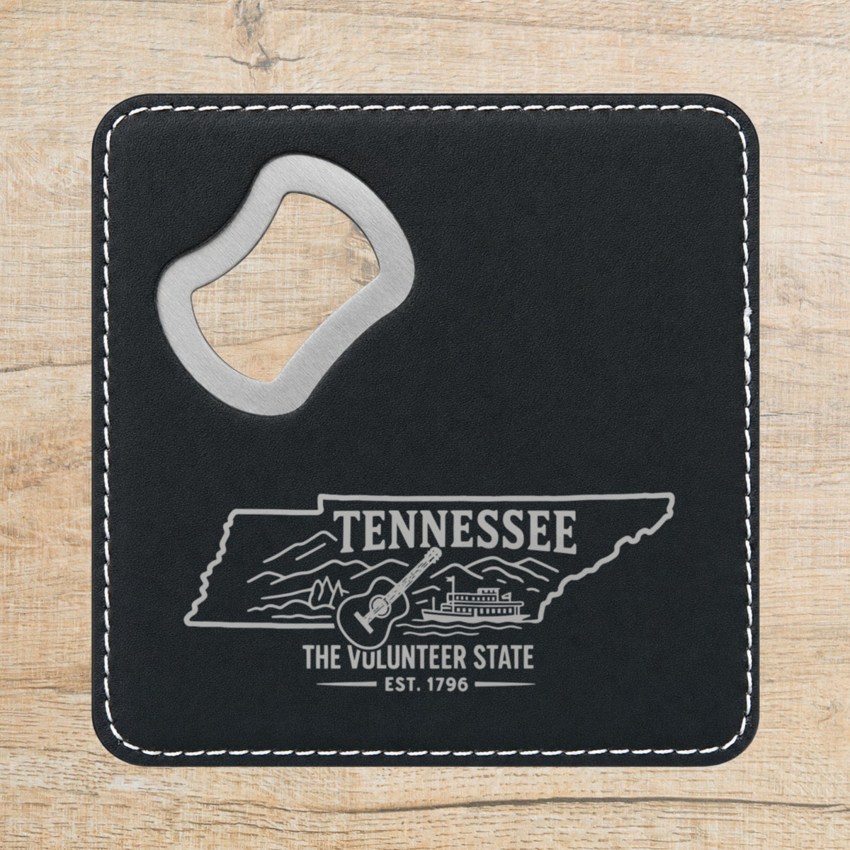 Black leatherette bottle opener coaster laser engraved with a Tennessee design of a guitar, a riverboat and the Smoky Mountains