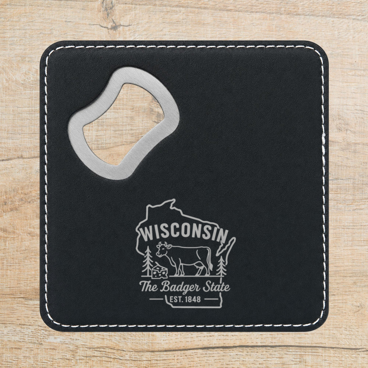 Black leatherette bottle opener coaster laser engraved with a Wisconsin design of a dairy cow and a wedge of cheese