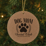 Brown leatherette Christmas ornament engraved with a Dog Mom Social Club crest design with a paw print and laurel wreath