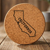 California round cork coaster engraved with the state outline and CALIFORNIA in hand-drawn brush lettering