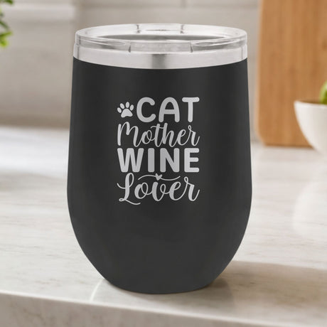 Black 12 oz stemless wine tumbler laser engraved with "Cat Mother Wine Lover" and a paw print, on a kitchen counter