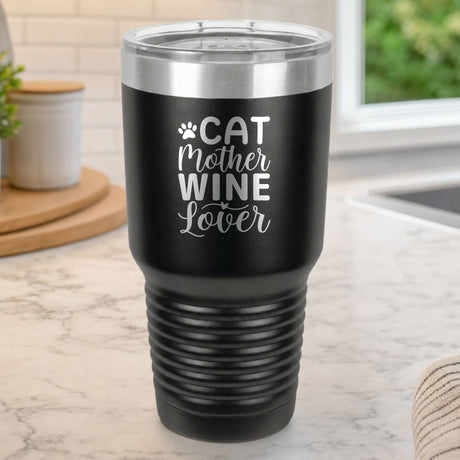 Black 30 oz tumbler laser engraved with "Cat Mother Wine Lover" and a paw print, on a kitchen counter