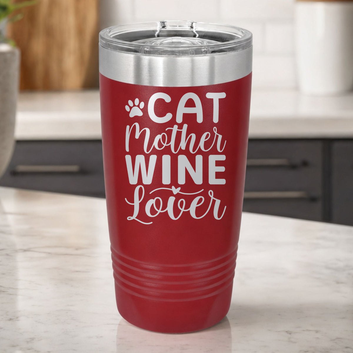 Maroon 20 oz tumbler laser engraved with "Cat Mother Wine Lover" and a paw print, on a kitchen counter