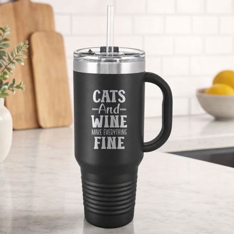Black 40 oz tumbler with handle and straw laser engraved with "Cats and Wine Make Everything Fine", on a kitchen counter