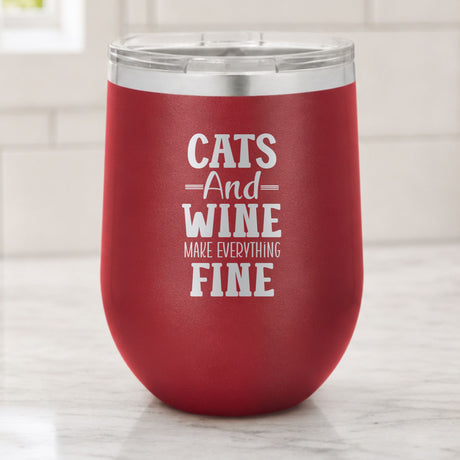 Maroon 12 oz stemless wine tumbler laser engraved with "Cats and Wine Make Everything Fine", on a kitchen counter
