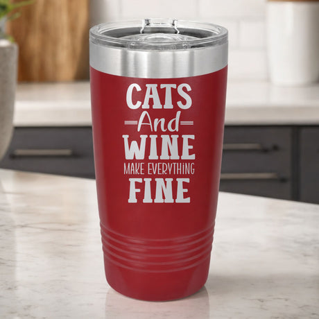 Maroon 20 oz tumbler laser engraved with "Cats and Wine Make Everything Fine", on a kitchen counter