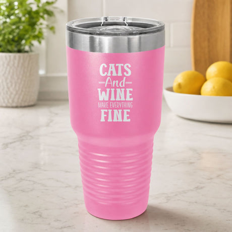 Pink 30 oz tumbler laser engraved with "Cats and Wine Make Everything Fine", on a kitchen counter