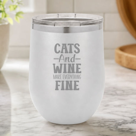 White 12 oz stemless wine tumbler laser engraved with "Cats and Wine Make Everything Fine", on a kitchen counter