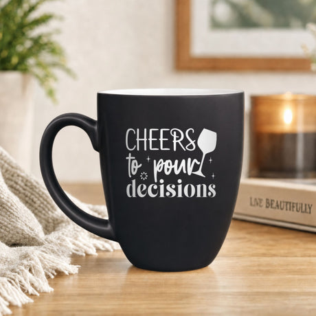 16 oz black ceramic coffee mug with "Cheers to Pour Decisions"