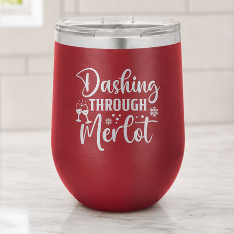 Maroon 12 oz stemless wine tumbler laser engraved with "Dashing Through Merlot", on a kitchen counter