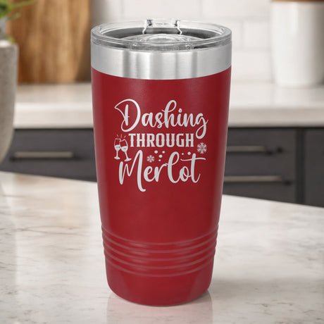 Maroon 20 oz tumbler laser engraved with "Dashing Through Merlot", on a kitchen counter