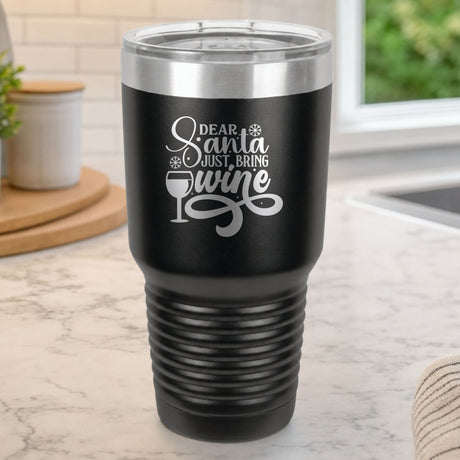Black 30 oz tumbler laser engraved with "Dear Santa, Just Bring Wine", on a kitchen counter