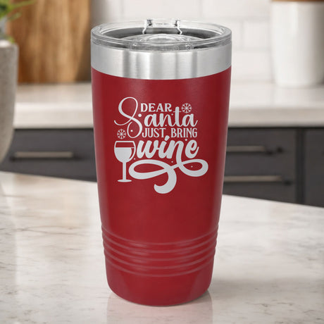 Maroon 20 oz tumbler laser engraved with "Dear Santa, Just Bring Wine", on a kitchen counter