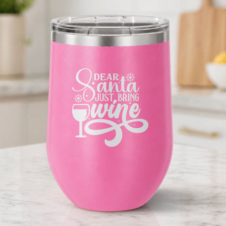 Pink 12 oz stemless wine tumbler laser engraved with "Dear Santa, Just Bring Wine", on a kitchen counter