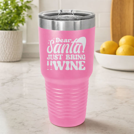 Pink 30 oz tumbler laser engraved with "Dear Santa, Just Bring Wine", on a kitchen counter