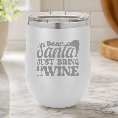 White 12 oz stemless wine tumbler laser engraved with "Dear Santa, Just Bring Wine", on a kitchen counter