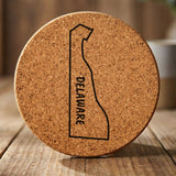 Delaware round cork coaster engraved with the state outline and DELAWARE running vertically