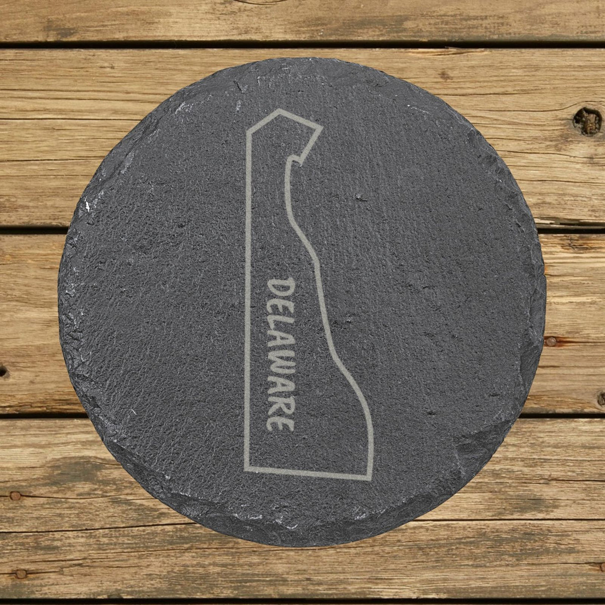 Delaware round slate coaster engraved with the state outline and DELAWARE running vertically