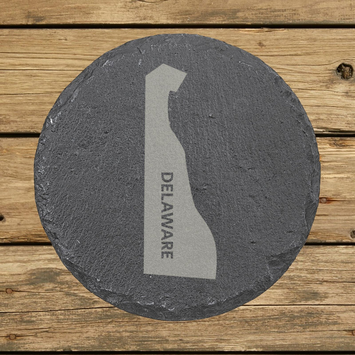 Delaware round slate coaster with the engraved state shape and DELAWARE running vertically