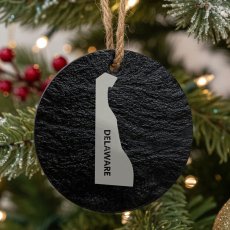 Delaware round slate Christmas ornament engraved with the state shape and DELAWARE in vertical lettering