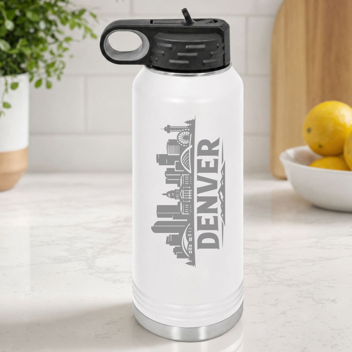 White 32 oz insulated water bottle laser engraved with the Denver, Colorado skyline running up the side, standing on a kitchen counter