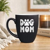 Black 16 oz ceramic coffee mug printed with a retro bubble letter Dog Mom design with a paw print