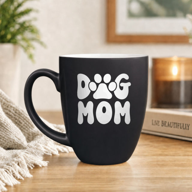 Black 16 oz ceramic coffee mug printed with a retro bubble letter Dog Mom design with a paw print