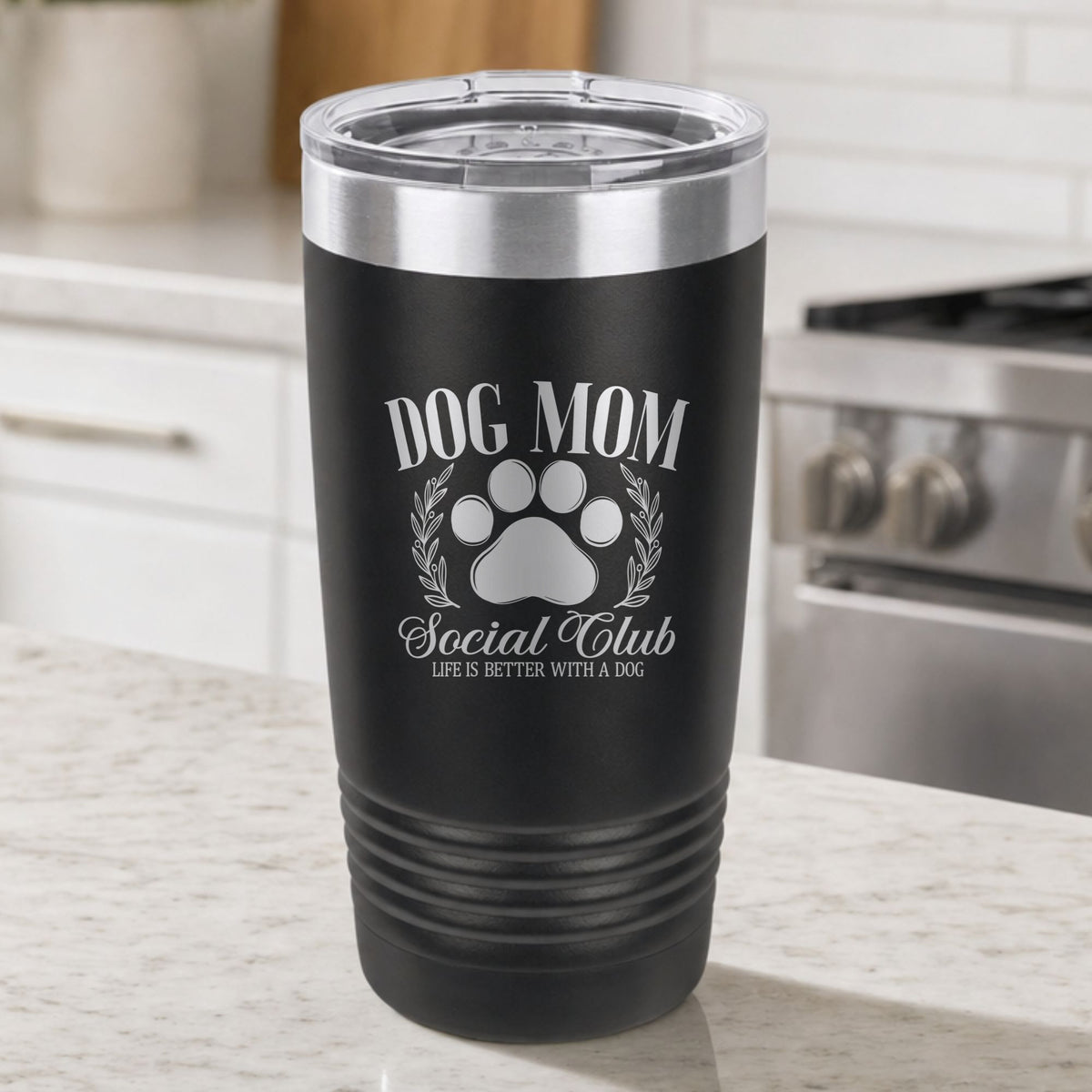 Black 20 oz tumbler laser engraved with the Social Club "Dog Mom" design, on a kitchen counter