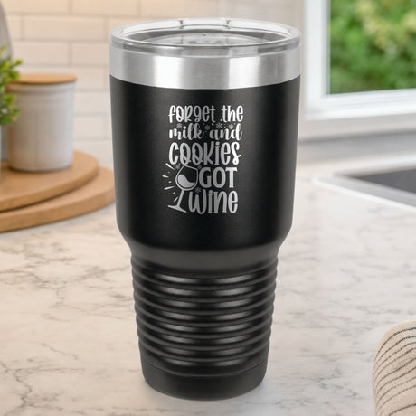Black 30 oz tumbler laser engraved with "Forget the Milk and Cookies, I've Got Wine", on a kitchen counter