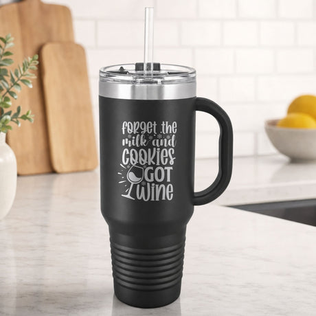Black 40 oz tumbler with handle and straw laser engraved with "Forget the Milk and Cookies, I've Got Wine", on a kitchen counter