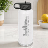 White 32 oz insulated water bottle laser engraved with the Frisco, Texas skyline running up the side, standing on a kitchen counter