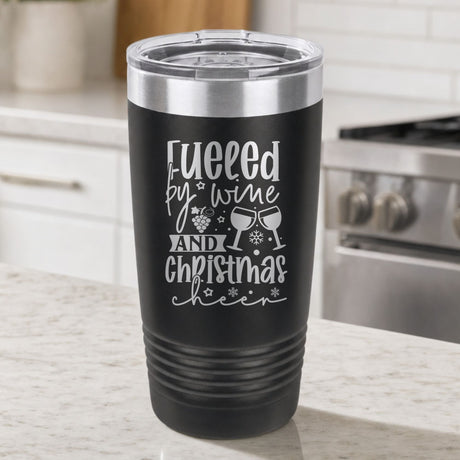 Black 20 oz tumbler laser engraved with "Fueled by Wine and Christmas Cheer", on a kitchen counter