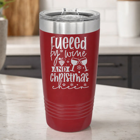 Maroon 20 oz tumbler laser engraved with "Fueled by Wine and Christmas Cheer", on a kitchen counter
