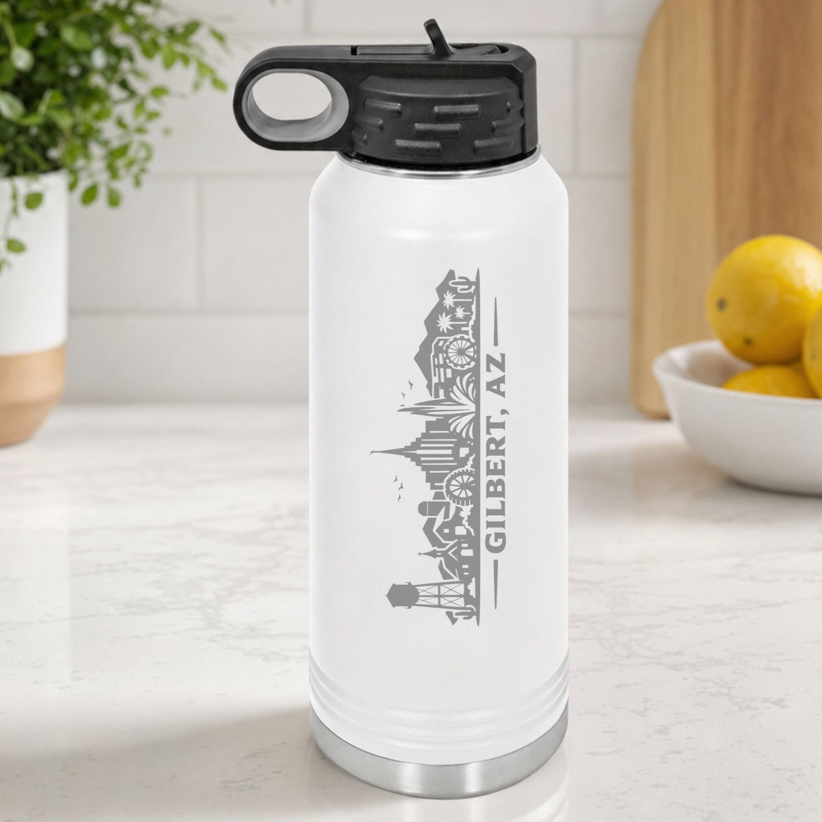 White 32 oz insulated water bottle laser engraved with the Gilbert, Arizona skyline running up the side, standing on a kitchen counter