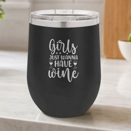 Black 12 oz stemless wine tumbler laser engraved with "Girls Just Wanna Have Wine", on a kitchen counter