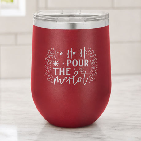 Maroon 12 oz stemless wine tumbler laser engraved with "Ho Ho Ho, Pour the Merlot", on a kitchen counter
