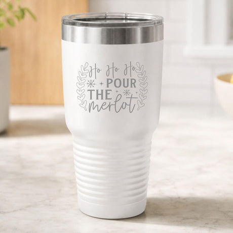 White 30 oz tumbler laser engraved with "Ho Ho Ho, Pour the Merlot", on a kitchen counter