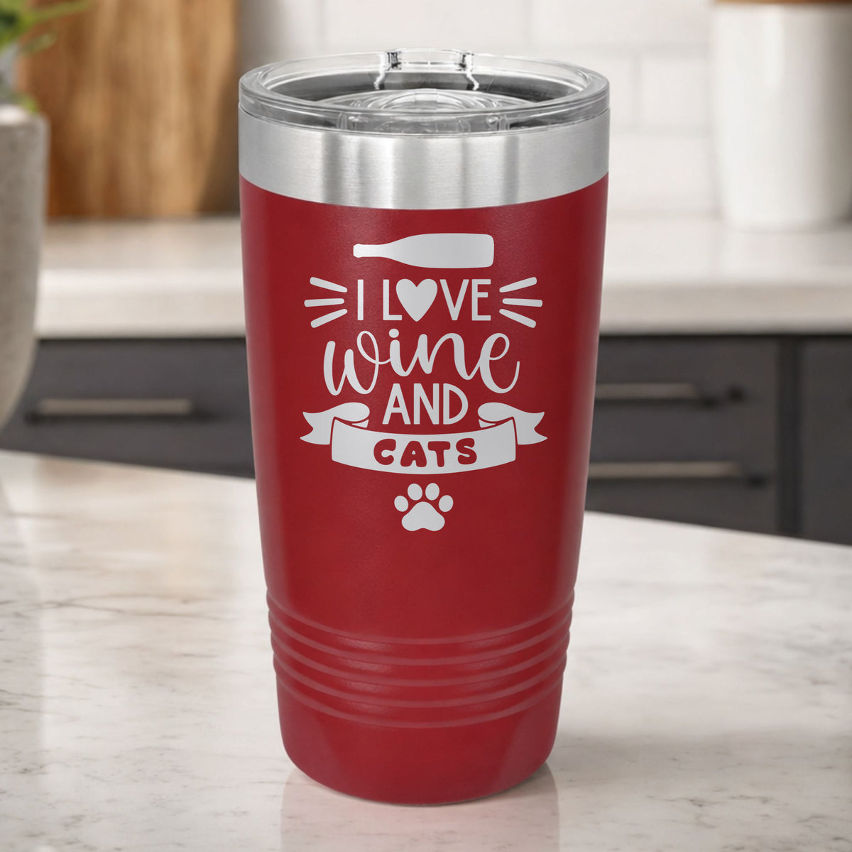 Maroon 20 oz tumbler laser engraved with "I Love Wine and Cats", a wine bottle, a heart and a paw print, on a kitchen counter