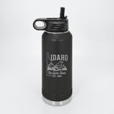 Black 32 oz insulated water bottle laser engraved with an Idaho design of a mountain bluebird, mountains and pines