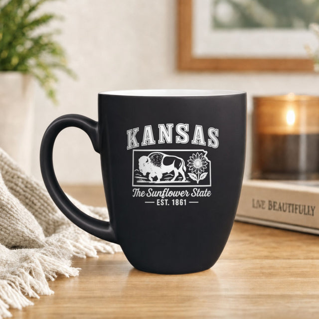 Black 16 oz ceramic coffee mug printed with the Kansas state outline and The Sunflower State