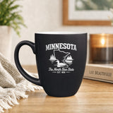 Black 16 oz ceramic coffee mug printed with the Minnesota state outline and The North Star State