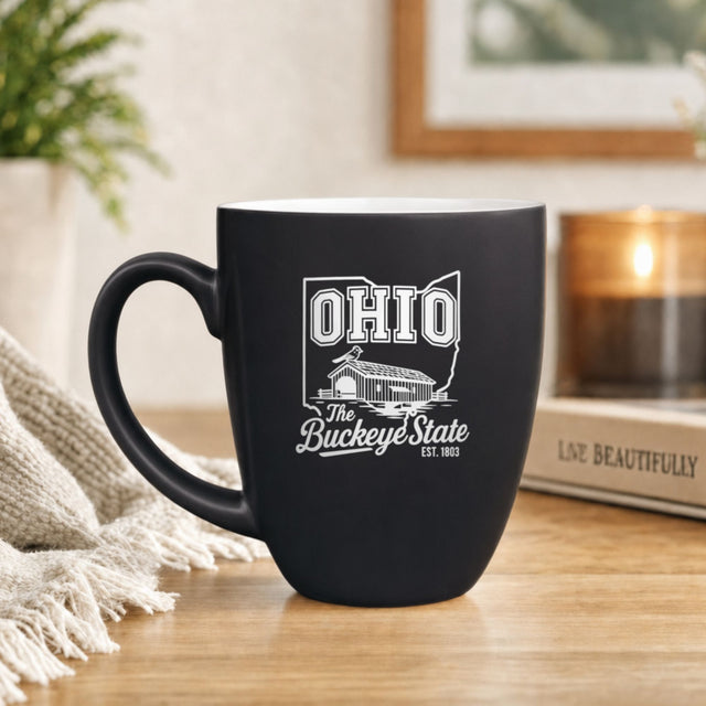 Black 16 oz ceramic coffee mug printed with the Ohio state outline and The Buckeye State