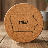 Iowa round cork coaster engraved with the state outline and IOWA in hand-drawn brush lettering
