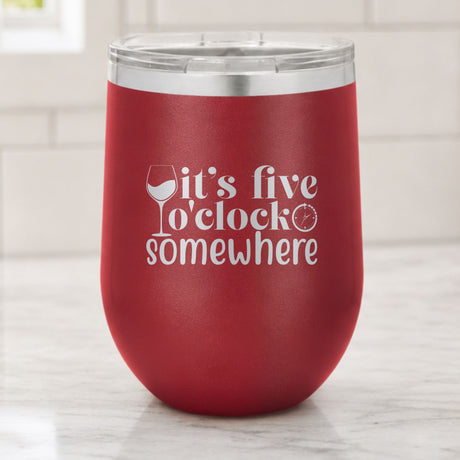 Maroon 12 oz stemless wine tumbler laser engraved with "It's Five O'Clock Somewhere", on a kitchen counter