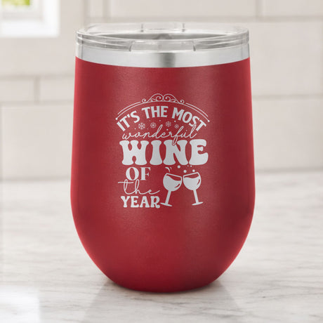 Maroon 12 oz stemless wine tumbler laser engraved with "It's the Most Wonderful Wine of the Year", on a kitchen counter