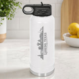 White 32 oz insulated water bottle laser engraved with the Laredo, Texas skyline running up the side, standing on a kitchen counter